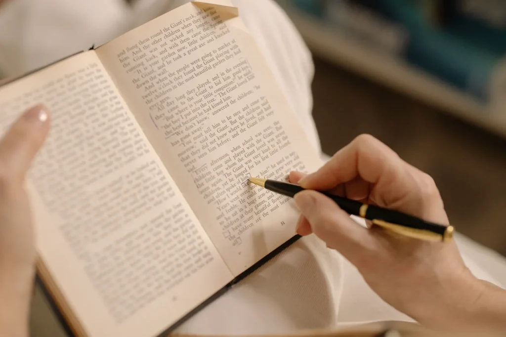 Mano subraya y anota ideas en las páginas de un libro abierto.