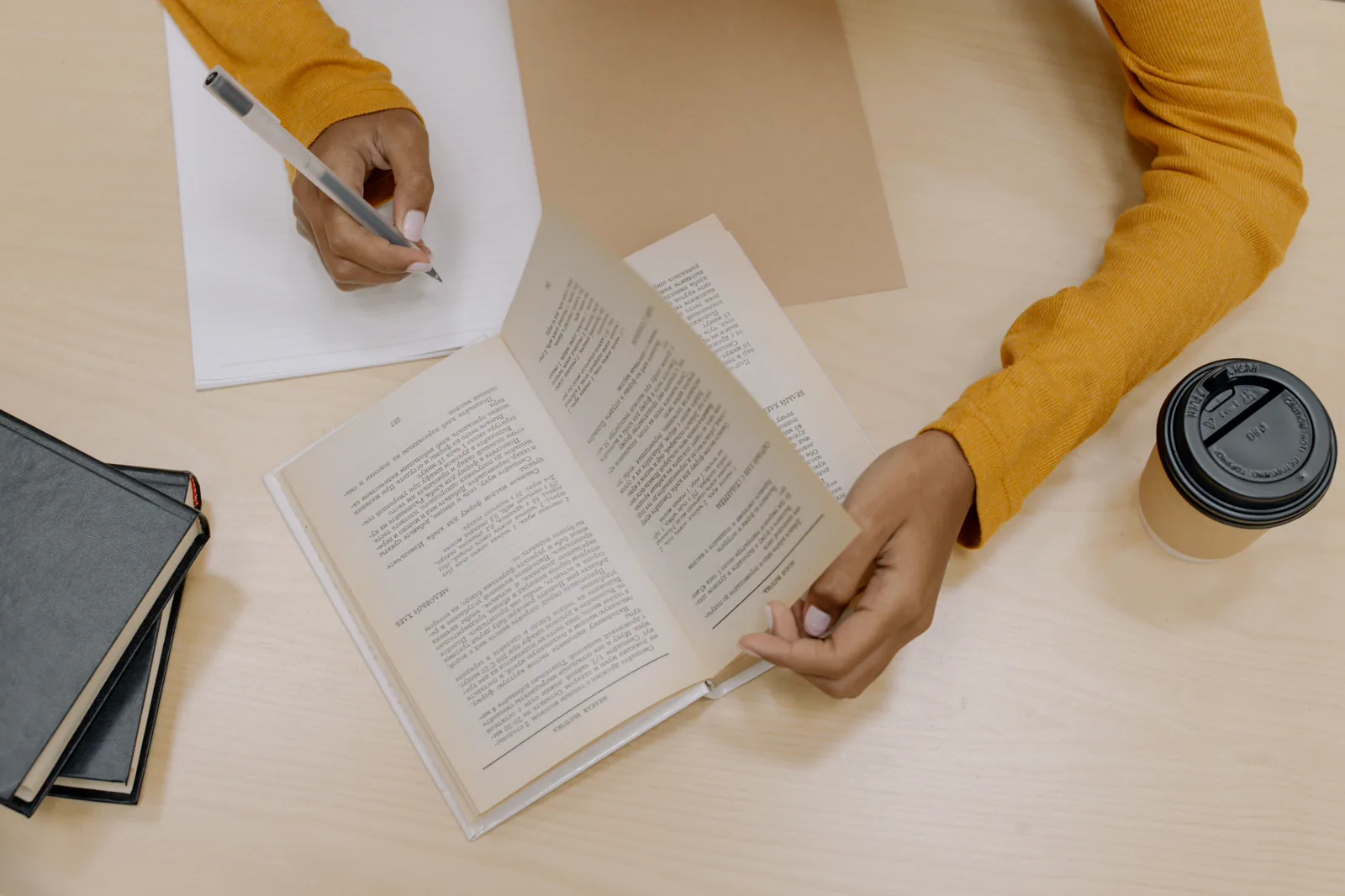 Persona toma notas junto a un libro abierto para recordar y relacionar ideas.