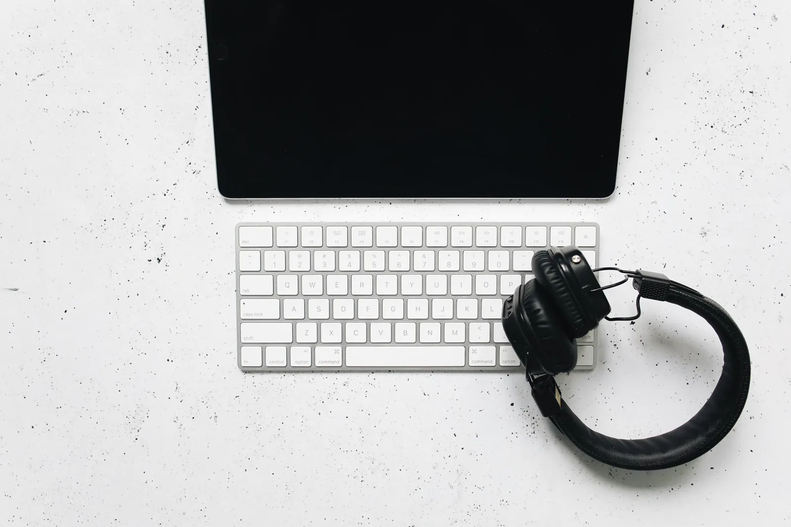 Tableta con teclado y auriculares sobre una mesa clara.