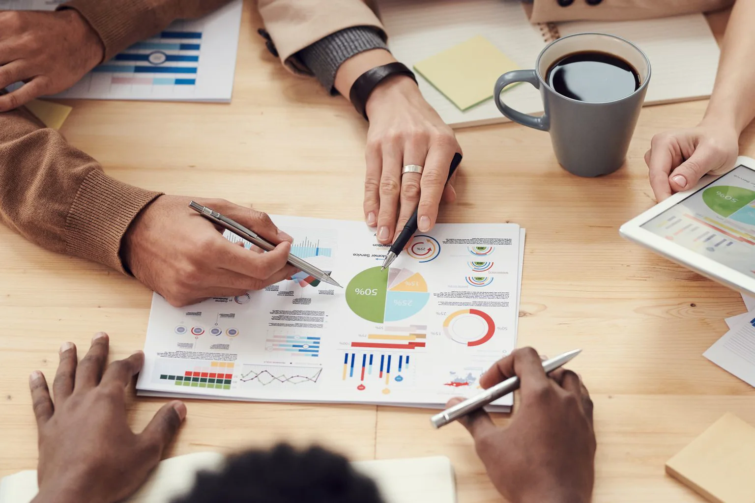 Equipo revisa gráficos y coordina decisiones alrededor de una mesa