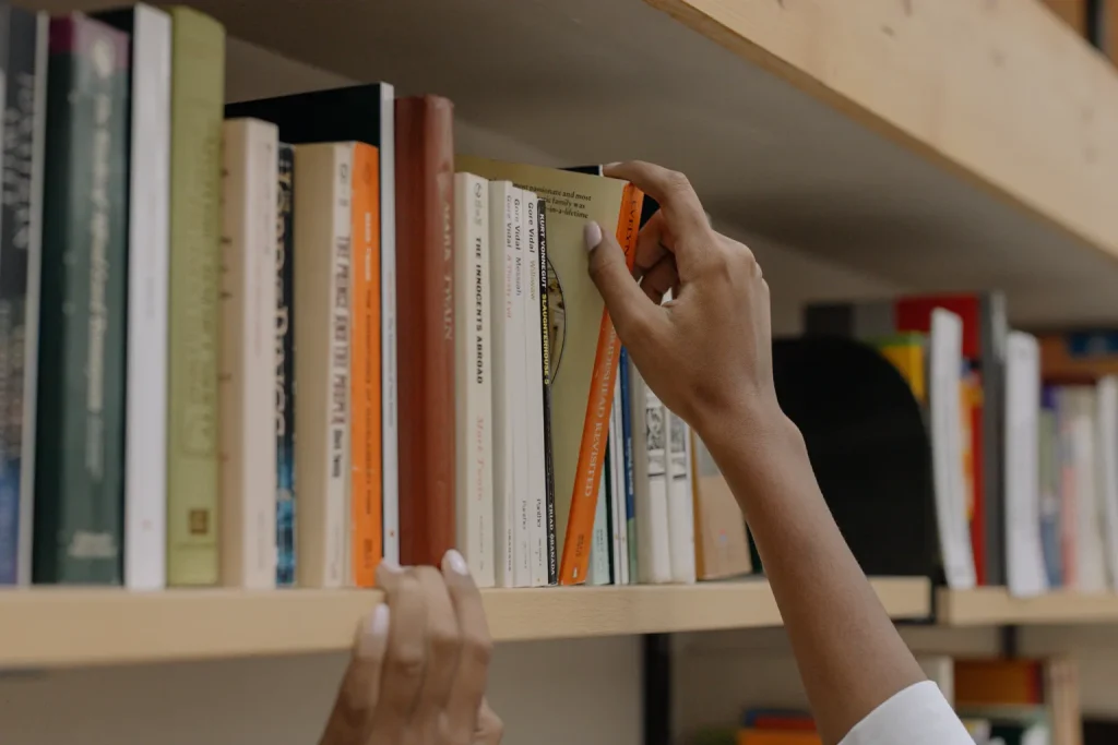 Persona elige un libro de un estante de biblioteca.