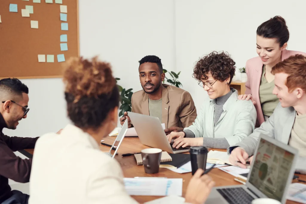Equipo reunido revisa el trabajo y distribuye responsabilidades alrededor de una mesa