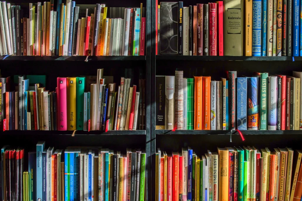 Lector elige un libro entre estantes de una biblioteca
