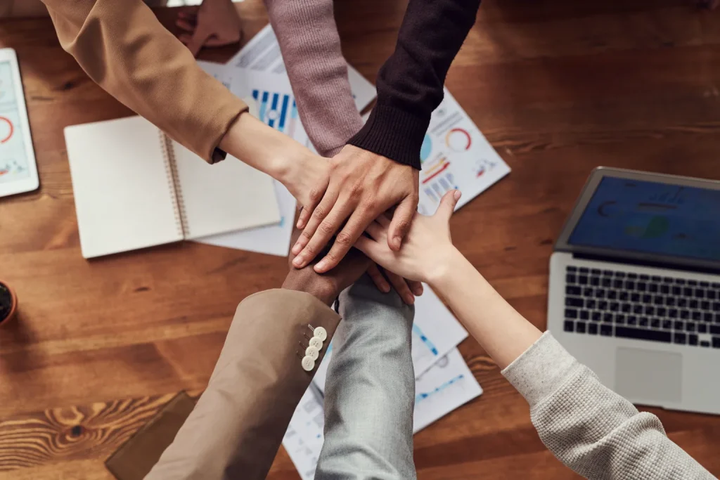 Equipo une sus manos sobre una mesa con gráficos de trabajo al fondo