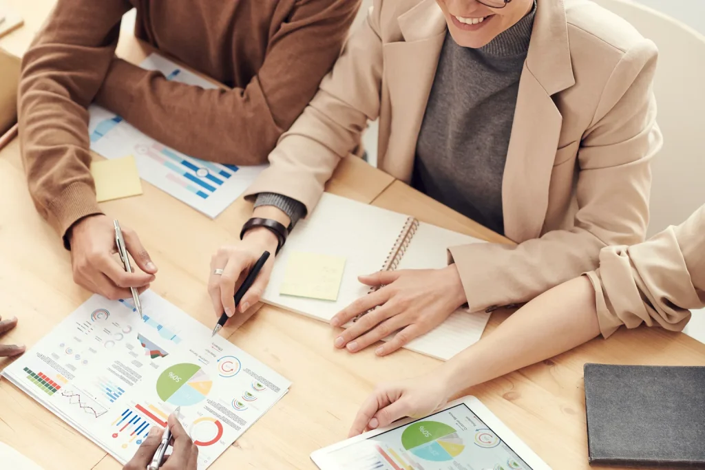 Equipo diverso revisa información y toma notas alrededor de una mesa de trabajo