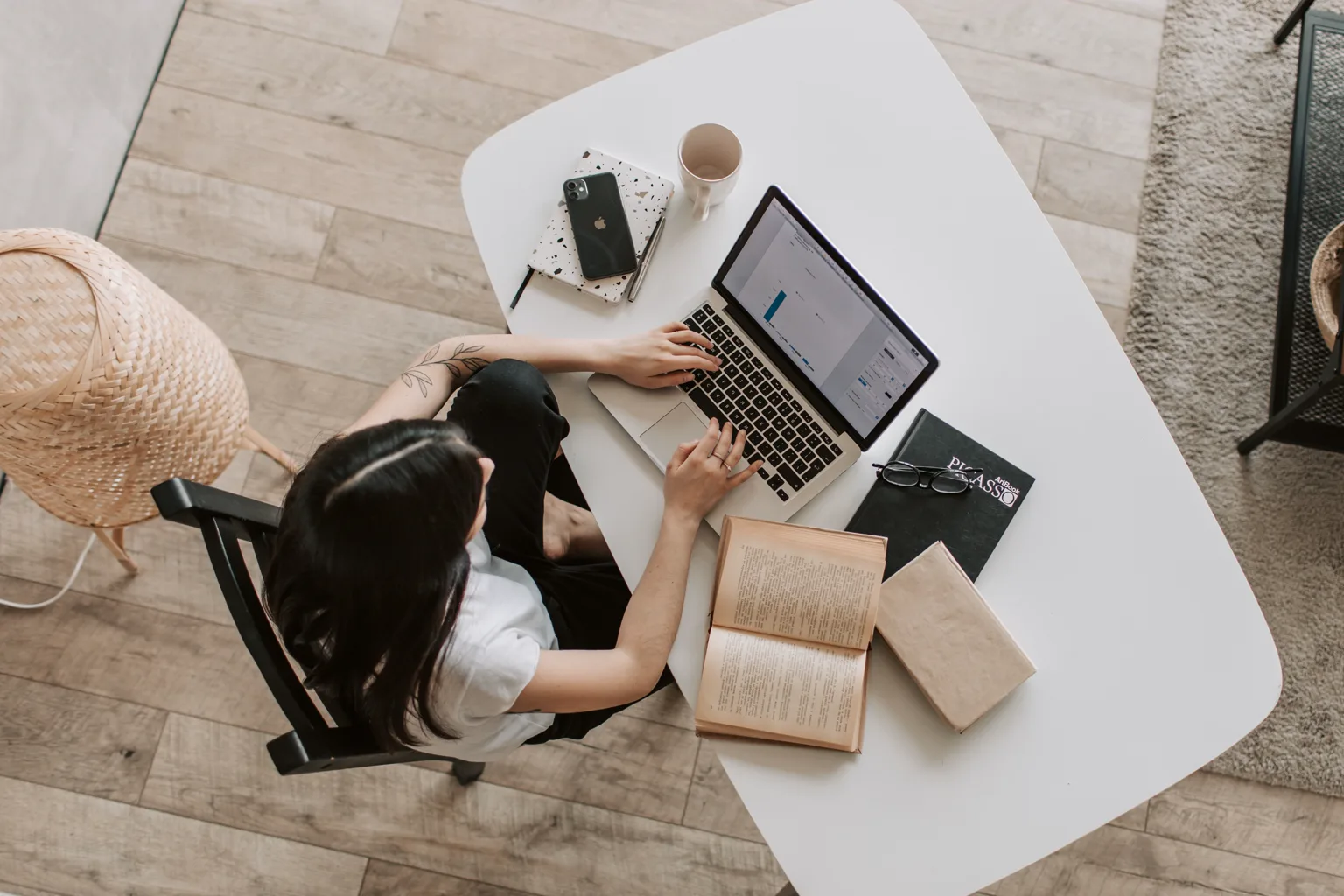 Profesional trabaja con un portátil junto a libros y cuadernos sobre una mesa