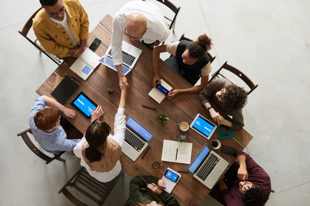 Equipo profesional reunido alrededor de una mesa con portátiles y notas de trabajo