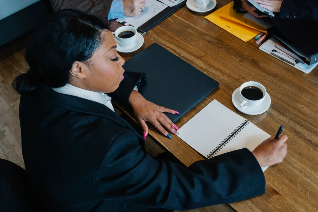 Profesional revisa documentos y escribe en una libreta durante una reunión
