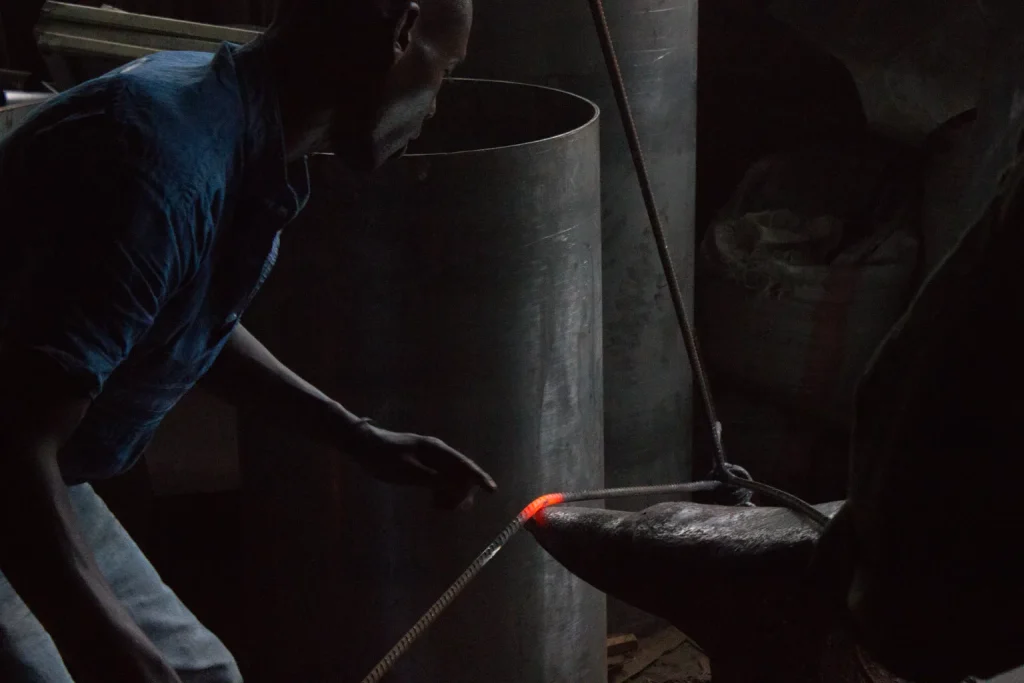 Trabajador en un taller de metal junto a una pieza calentada, imagen que representa capacidad operativa y ritmo de producción
